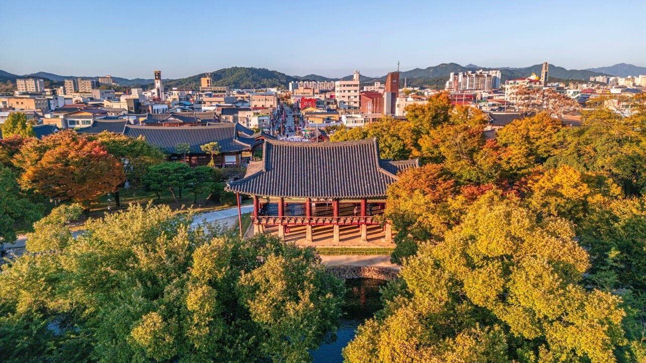 가을 나무에 둘러싸인 광한루와 그 뒤로 펼쳐진 남원 시가지
