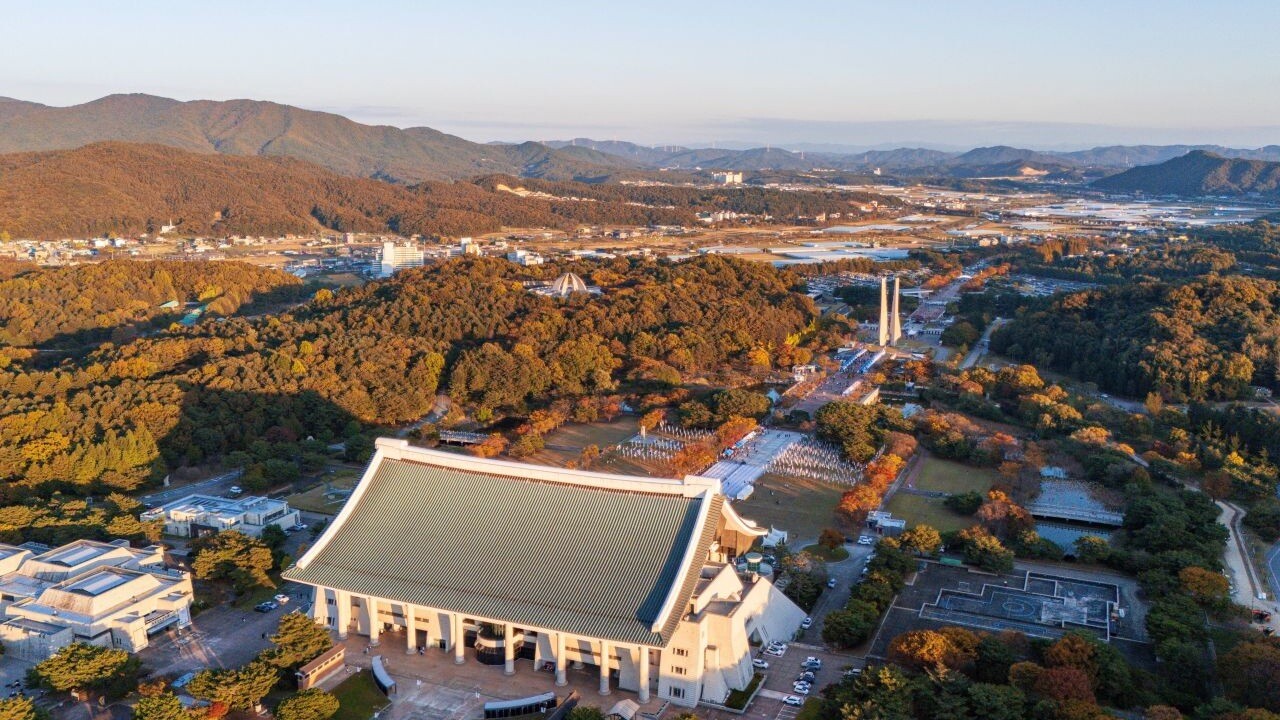 겨레의 집 지붕과 경내 숲을 내려다본 항공 전경